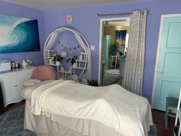 Bright and calming treatment room with lavender walls and ocean wave painting
