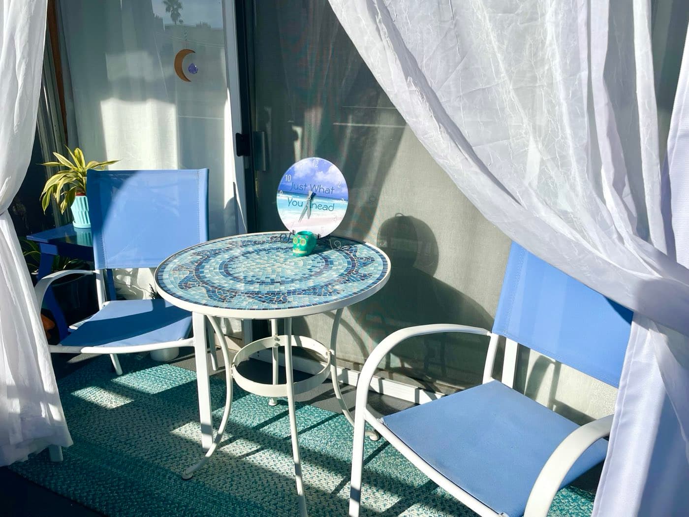 Sunlit patio seating area with mosaic table and sheer curtains